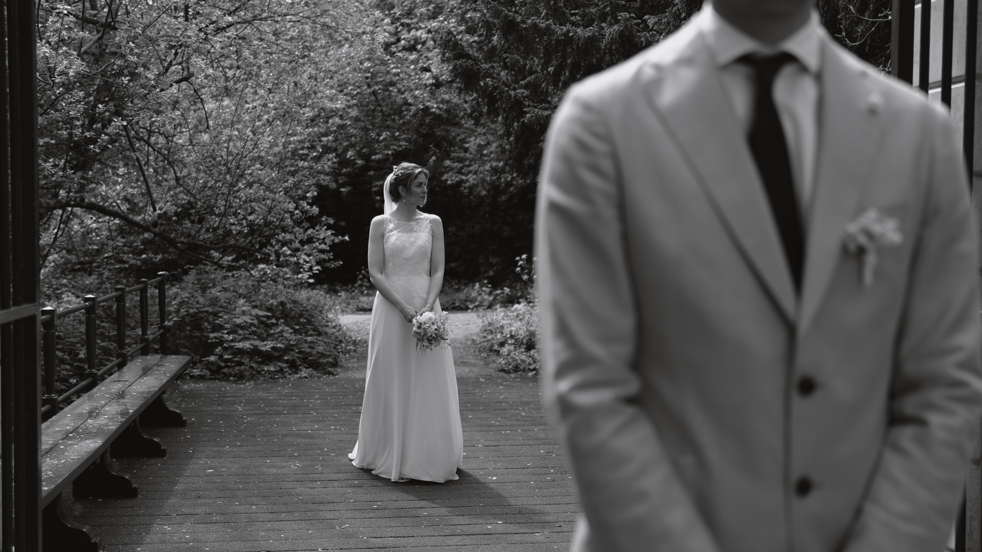 Bruid die achter de bruidegom staat voor een shot in de trouwfilm