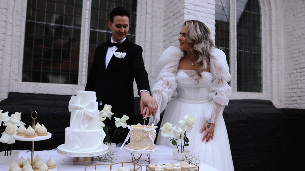 Bruidspaar snijd taart aan op bruiloft